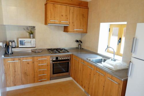 cocina con armarios de madera, fregadero y nevera en Casa Can Pep - Astbury Formentera, en Sant Ferran de Ses Roques
