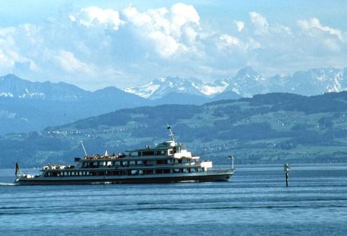 a large boat on the water with mountains in the background at Hotel St Elisabeth in Allensbach