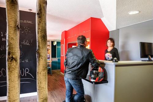 a man standing at a counter with a woman behind it at hotelF1 Grenoble Université in Gières