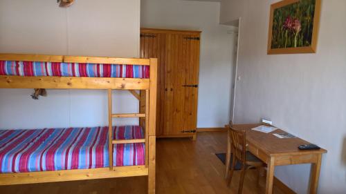 a bedroom with a bunk bed and a wooden table at Les Fauvettes in Saint-Léger-les-Mélèzes