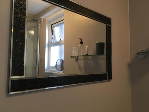 a mirror on the wall of a bathroom with a window at Southville Guest House in Weymouth