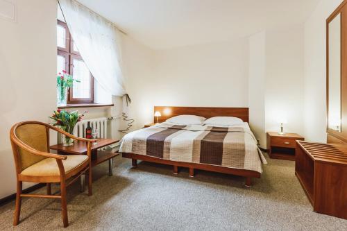 a bedroom with a bed and a desk and a chair at Hotel Gromada Toruń in Toruń