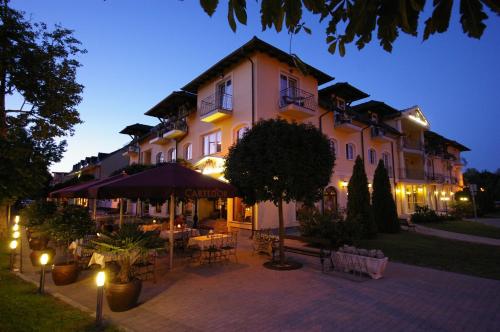 a large building with tables and chairs in front of it at Xavin Wellness Hotel & Restaurant in Harkány