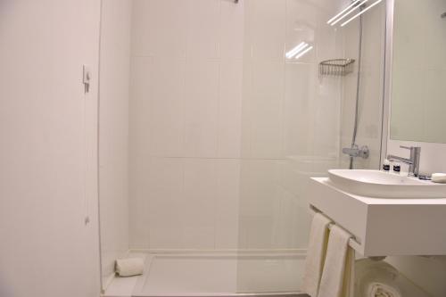 a white bathroom with a shower and a sink at Hotel Sol Algarve by Kavia in Faro