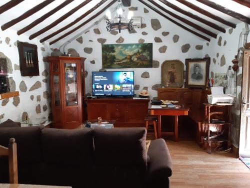 ein Wohnzimmer mit einem Sofa und einem TV in der Unterkunft La Piedra Viva Agüimes , Siete hermanos in Agüimes