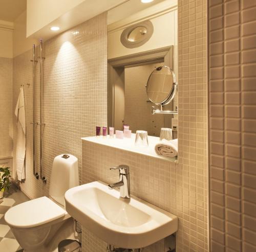 a bathroom with a sink and a toilet and a mirror at Rosersbergs Slottshotell in Rosersberg