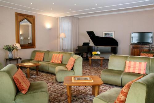 a living room with green couches and a piano at Hotel Moderno in Premeno