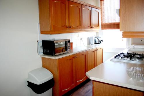 a kitchen with wooden cabinets and a microwave on a counter at Hartland Apartments - near Cliffs Pavilion in Southend-on-Sea