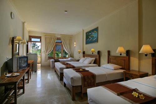 a hotel room with four beds and a television at Febri's Hotel & Spa in Kuta