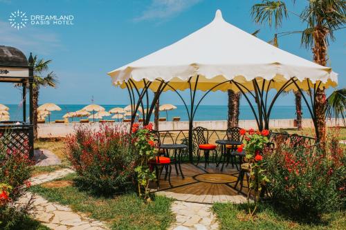 Dreamland Oasis Hotel في شاكفي: طاولة وكراسي تحت مظلة على الشاطئ