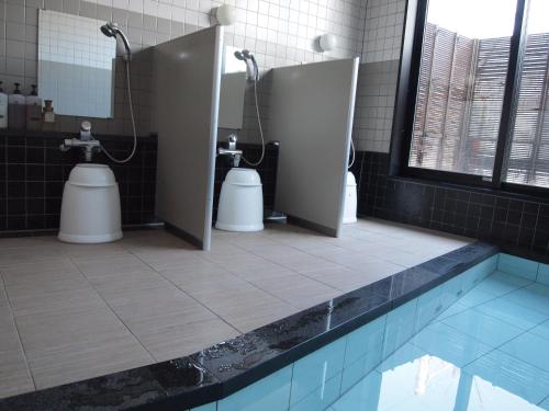 een badkamer met 3 toiletten en een zwembad bij Murayama Nishiguchi Hotel in Murayama