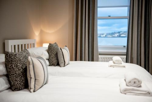 two beds in a hotel room with a window at The Old Customs House in Banff