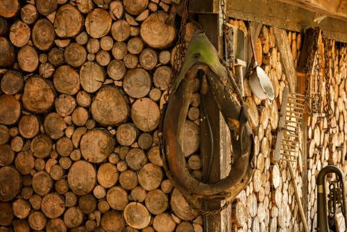a wall full of wooden logs with a horseshoe at Hotel Zur Linde Dein Self Check In in Michendorf