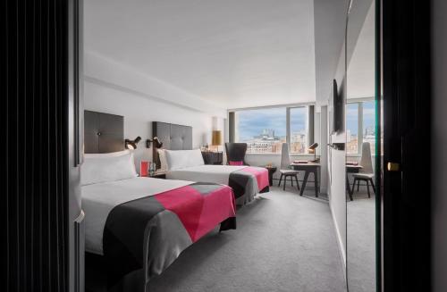 a hotel room with two beds and a table and chairs at Sea Containers London in London