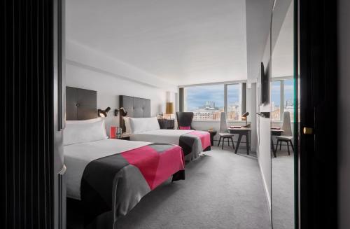 Cette chambre d'hôtel comprend deux lits, une table et des chaises. dans l'établissement Sea Containers London, à Londres
