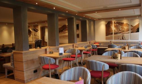 レッヒにあるホテル ガルニ レルヒェンホーフの木製テーブルと赤い椅子が備わるレストラン