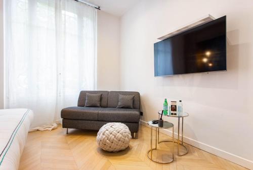 Il comprend un salon avec une chaise et une télévision à écran plat. dans l'établissement Cosy & Luxury Kléber Trocadéro Arc de Triomphe, à Paris