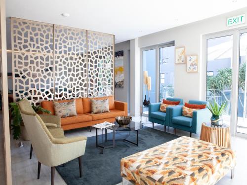 a living room with an orange couch and chairs at Zest Boutique Hotel by The Living Journey Collection in Cape Town