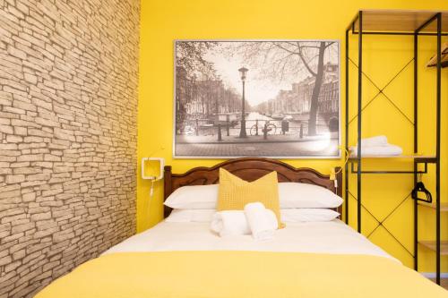 a yellow bedroom with a bed with two pillows at Tower Bridge Rainbow Suites in London