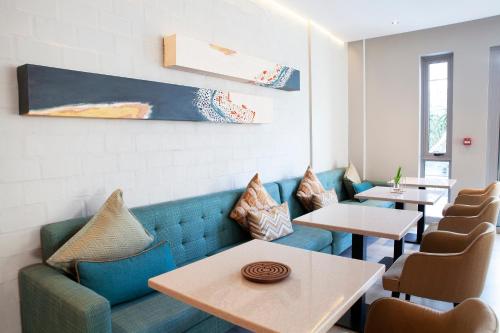 a restaurant with a blue couch and tables and chairs at Zest Boutique Hotel by The Living Journey Collection in Cape Town