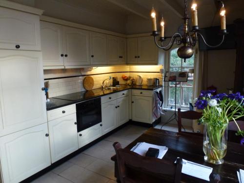 a kitchen with white cabinets and a table with a vase of flowers at Vakantiewoning Salland in Markelo