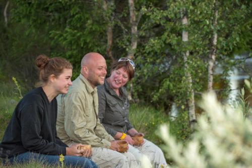 a group of three people sitting on the grass at Sæteråsen Hytter & Camping Trysil in Trysil