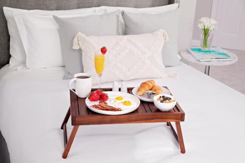 a breakfast tray with breakfast foods on a bed at Inn at Harbor Hill Marina in Niantic