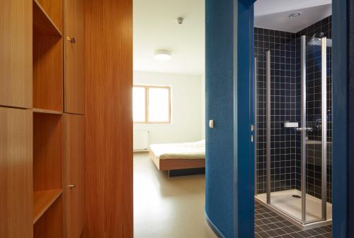 a bathroom with a glass shower and a bedroom at Youth Hostel Beaufort in Beaufort