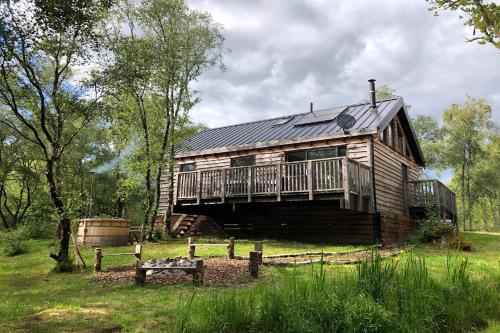 eine Blockhütte mit einer Veranda und einer Terrasse in der Unterkunft Loch Aweside Forest Cabins in Dalavich