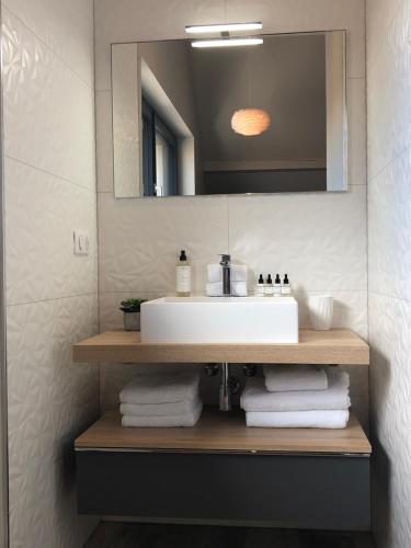 a bathroom with a sink and a mirror and towels at Gîte Wellness Le Six H in Andolsheim