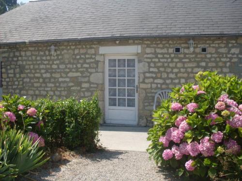 un edificio de piedra con una puerta blanca y flores rosas en Domaine Saint-Hilaire, en Saint-Hilaire-Petitville