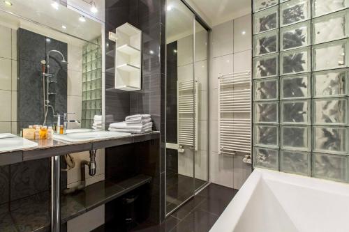 La salle de bains est pourvue d'une baignoire, de 2 lavabos et d'une douche. dans l'établissement Veeve - By Boulevard Saint Germain, à Paris