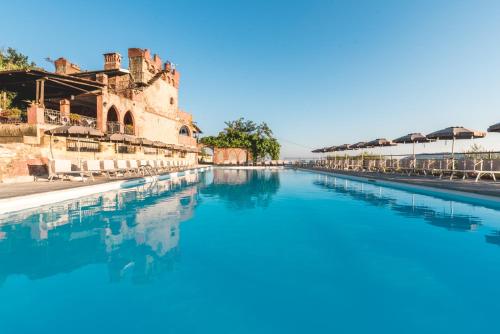 una piscina de agua azul frente a un edificio en Ippotur Medieval Resort, en Castelnuovo Magra
