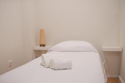 a white bed with towels on top of it at ZD Moreira Flats A By PortoProperties4You in Porto