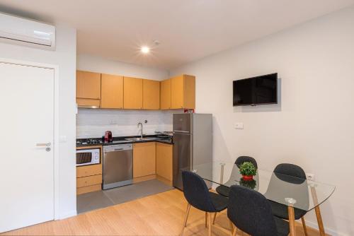 a kitchen with a glass table with chairs and a refrigerator at ZD Moreira Flats A By PortoProperties4You in Porto