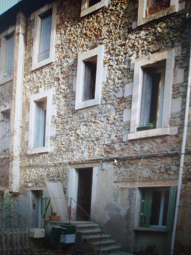 an old stone building with windows and a staircase at F1 duplex Bleuet Rénové in Lamalou-les-Bains