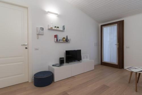 ein weißes Wohnzimmer mit einem TV und einer Tür in der Unterkunft Italianway - Vigevano 13 in Mailand