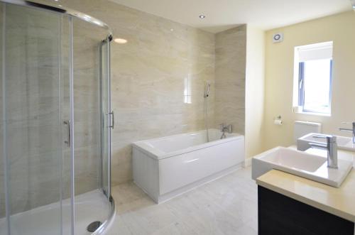 a bathroom with a shower and a tub and a sink at Property 260 - Moyard in Moyard