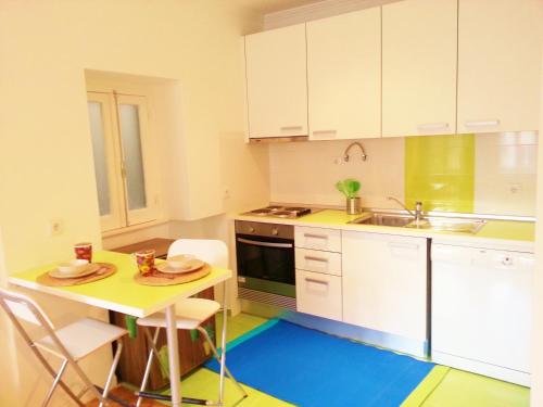 リスボンにあるEco Green Studio Apartmentのキッチン(白いキャビネット、テーブル、シンク付)