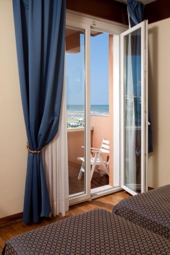 a bedroom with a sliding glass door with a view of the ocean at Hotel Bellevue in Rimini