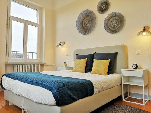 - une chambre dotée d'un grand lit avec des oreillers jaunes et bleus dans l'établissement Le XI - Suite Colmar Gare, à Colmar