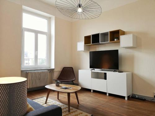 un salon avec une télévision, un canapé et une table dans l'établissement Le XI - Suite Colmar Gare, à Colmar