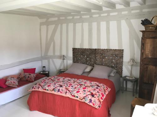 a bedroom with a bed with a red comforter at L'Atelier de Tess in Le Bec-Hellouin