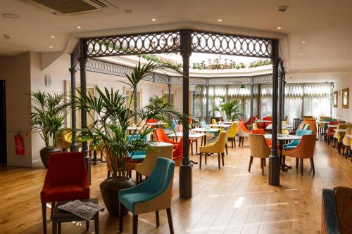 un restaurante con mesas, sillas y plantas en Gonville Hotel en Cambridge