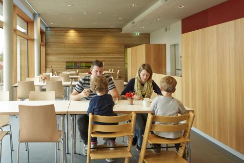 a woman and two children sitting at a table in a restaurant at Youth Hostel Beaufort in Beaufort