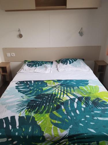 a bed with a colorful comforter and pillows on it at BVCO LOCATIONS PROCHE CHATEAUX ET BEAUVAL DANS LE LOIR et CHER in Onzain
