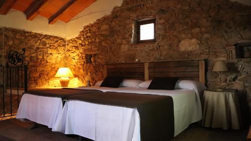 a bedroom with a bed and a stone wall at La Caseta Vella in Falset