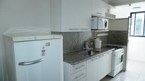 uma cozinha com um frigorífico branco e um lavatório em Golden Flat em João Pessoa