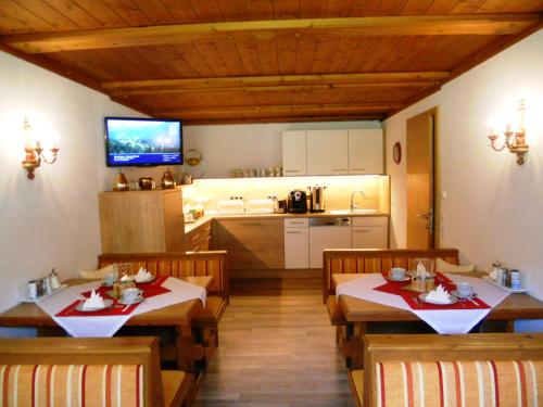 a dining room with two tables and a kitchen at Pension Zeitlos in Wagrain