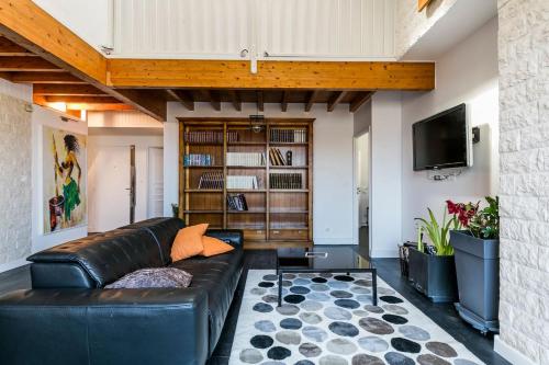 a living room with a leather couch and a tv at Penthouse 120 m2 vue imprenable Lattes in Lattes